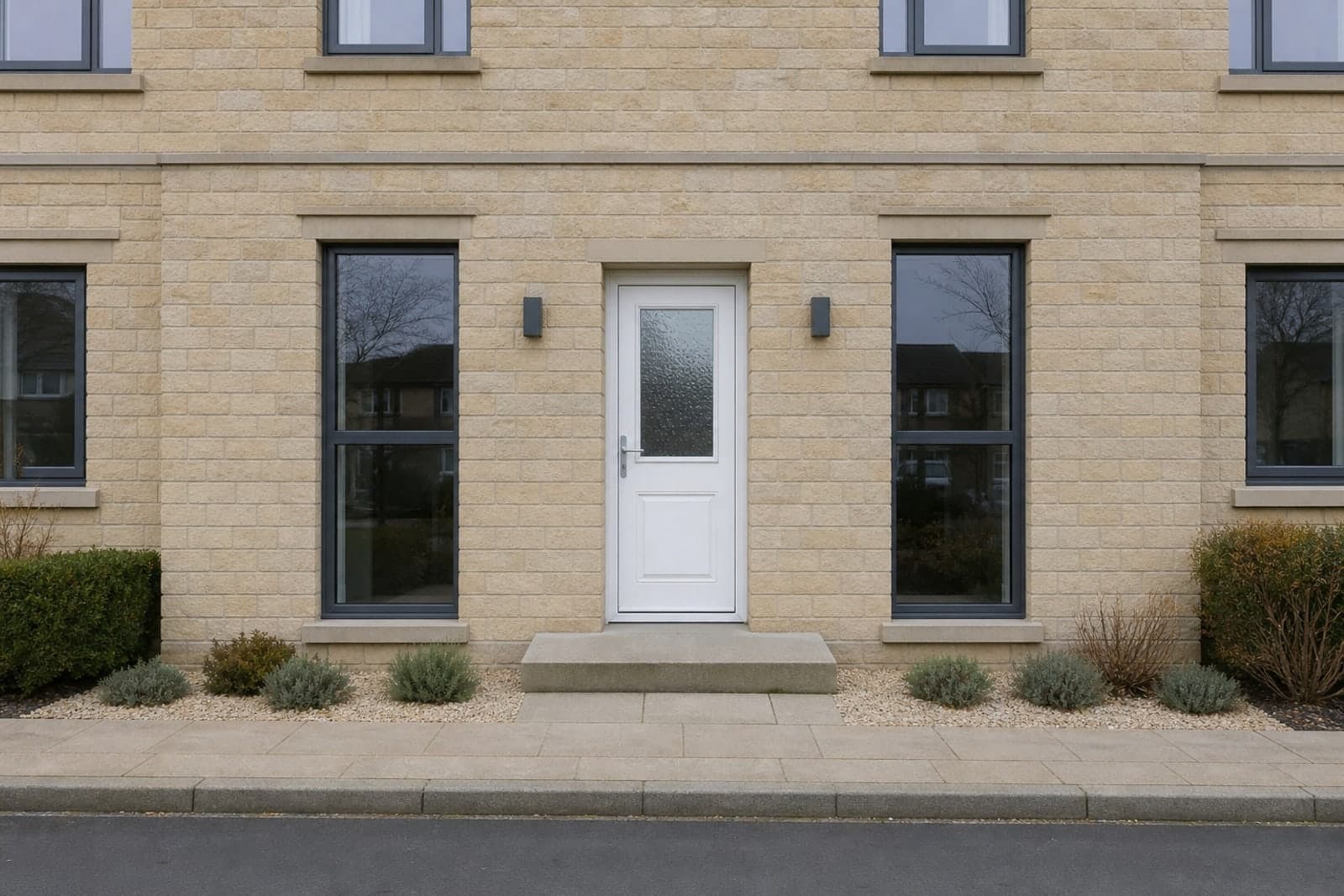 A contemporary stone-faced house with a dated white uPVC front door and bubbled glass.