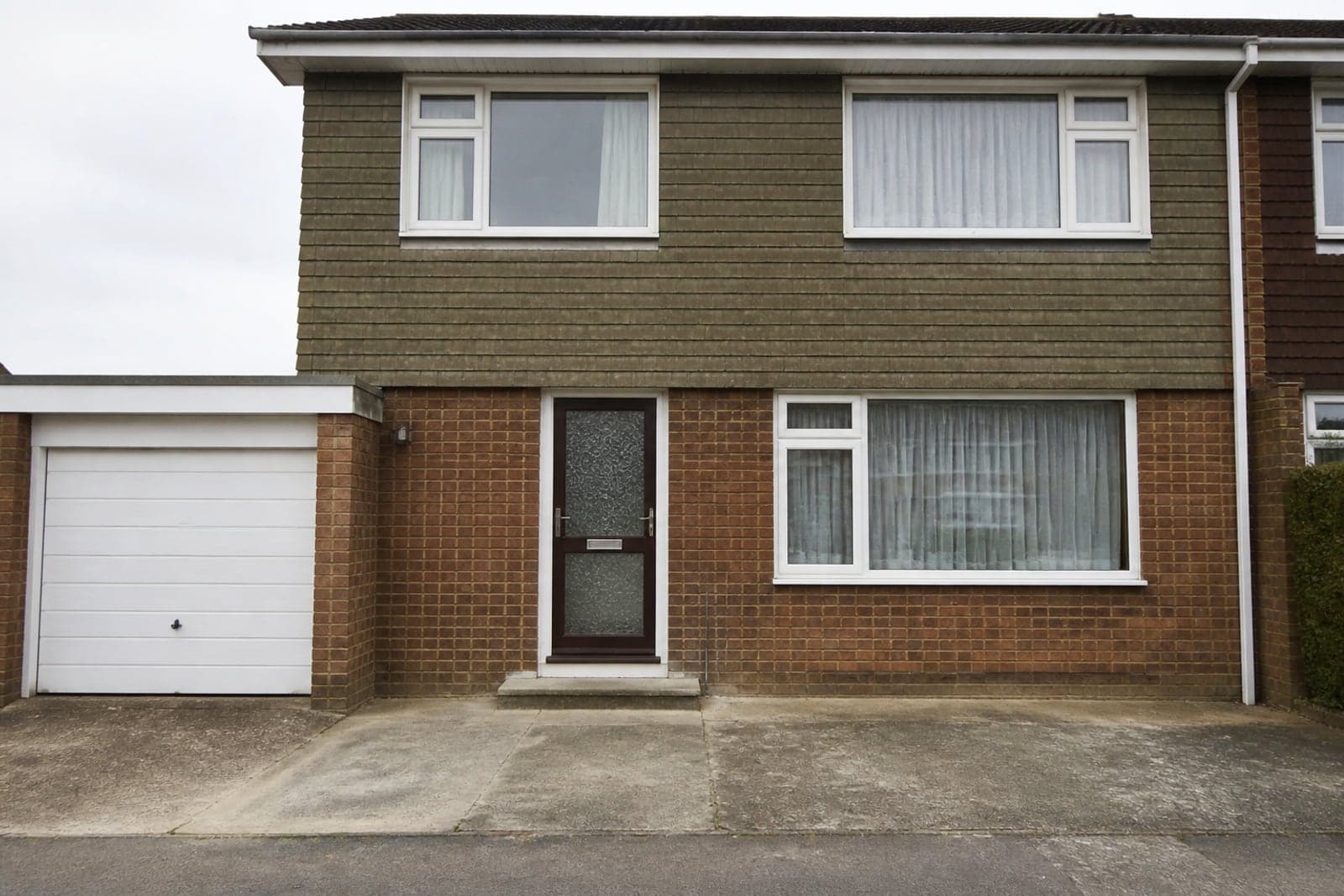 A 1970s semi-detached house with a dated brown front door and patterned obscure glass.