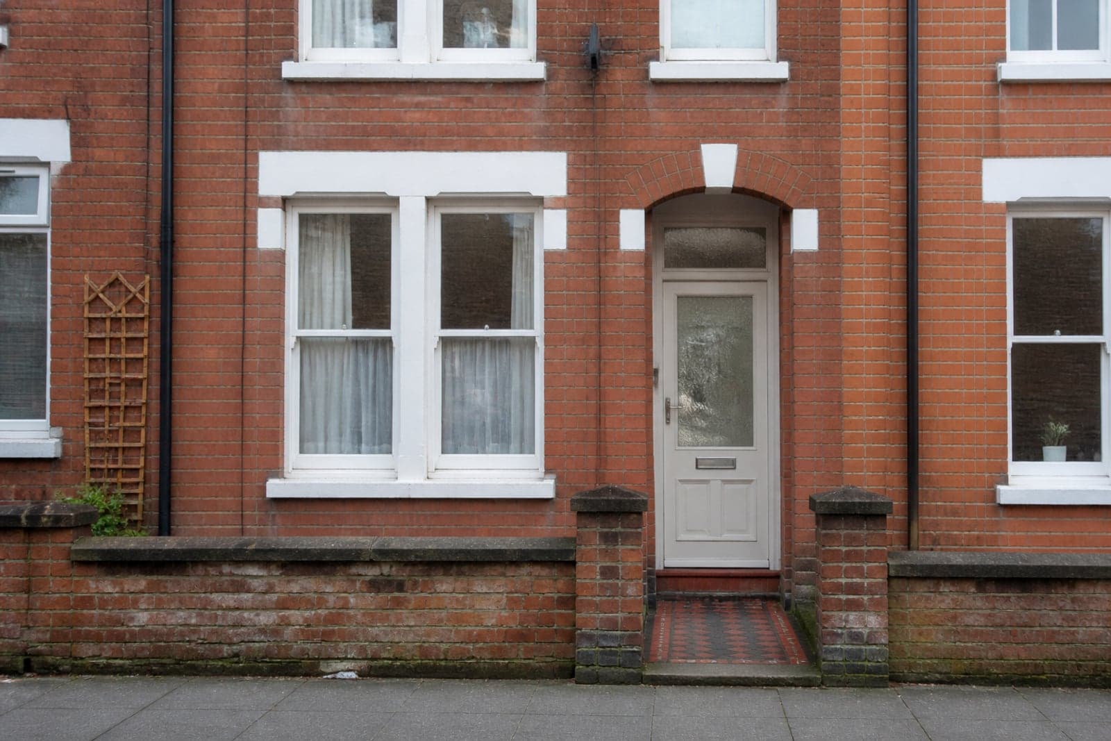 A Victorian red-brick terraced house with a dated white uPVC front door and bubbled glass.