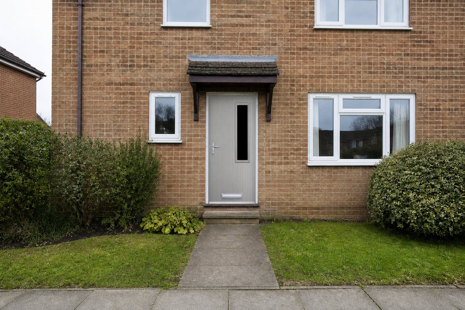 A composite front door fitted into the opening of a brick house.